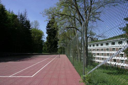a tennis court with a fence next to a building at Parc Hotel Alvisse in Luxembourg