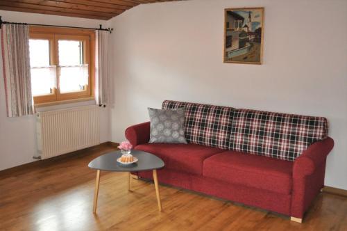 a living room with a red couch and a table at Ferienwohnung Baumgartner in Bad Hindelang