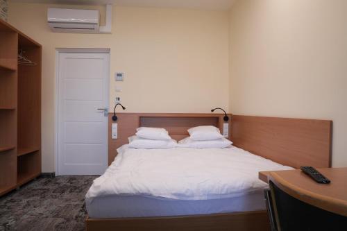 a bedroom with a bed with white sheets and a desk at Motelik Grosar Jasło in Jasło