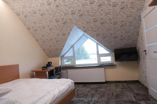 a attic bedroom with a bed and a window at Motelik Grosar Jasło in Jasło