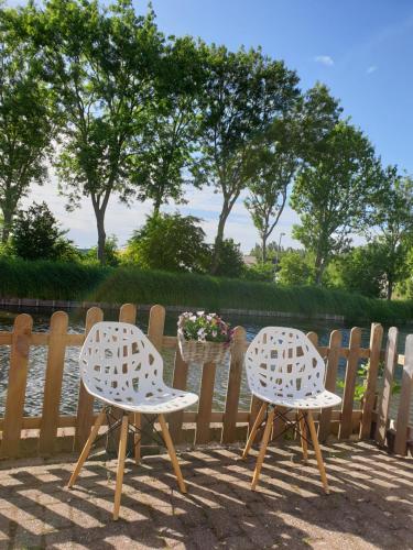two chairs sitting next to a fence with flowers at Logeren op Dijk43 in Broek op Langedijk