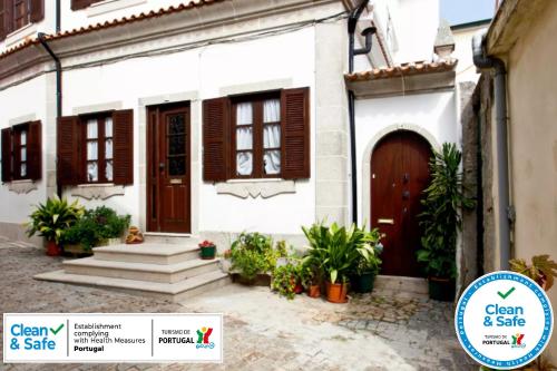 a white house with a brown door and stairs at Casa da Foz in Porto