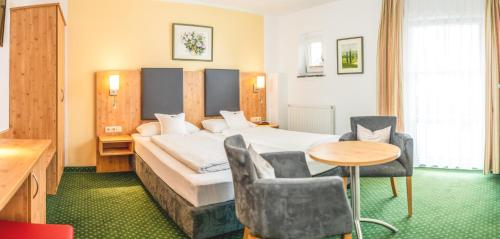 a hotel room with a bed and a table and chairs at Hotel Steffl Garni inkl Chiemgau Karte in Ruhpolding