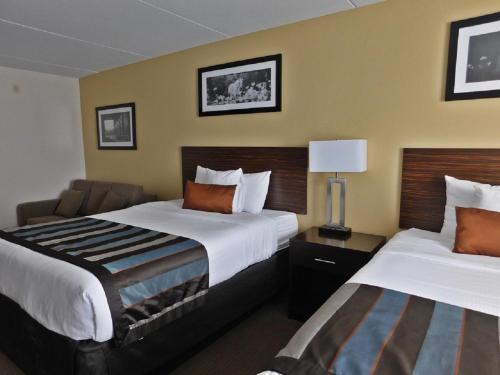 a hotel room with two beds and a chair at Wingate by Wyndham Bowling Green in Bowling Green
