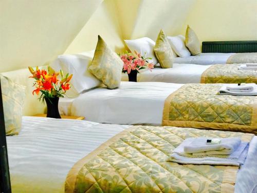 three beds in a room with flowers on them at Grainger House Hotel in Newcastle upon Tyne