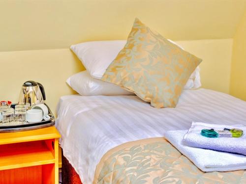 a bed with a pillow and a table with a night stand at Grainger House Hotel in Newcastle upon Tyne