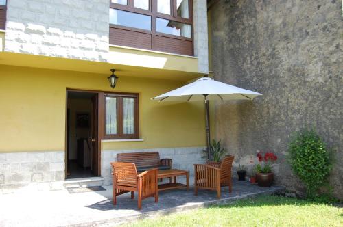 a table and chairs with an umbrella next to a building at Gestiona2R - Casa Dos Carmenes, caminando a la playa, ideal familias in Llanes