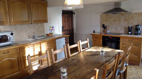 una cocina con una gran mesa de madera y sillas en Gite de la Haute Verdière, en La Neuville-du-Bosc