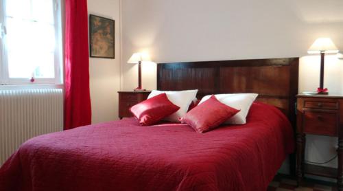 una camera da letto con un letto rosso con due cuscini rossi e bianchi di Gite de la Haute Verdière a La Neuville-du-Bosc