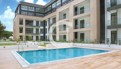 an apartment building with a swimming pool in front of a building at Embassy Gardens by Clifton Homes in Accra