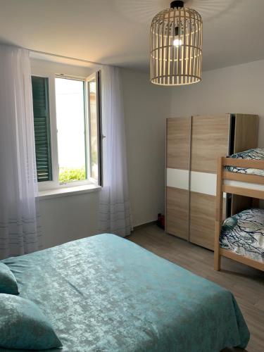 a bedroom with a bed and a window and a chandelier at Apartman Višković Koromačno in Koromačno