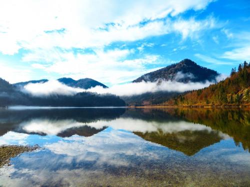 a reflection of a mountain in a lake with clouds at Hotel Steffl Garni inkl Chiemgau Karte in Ruhpolding