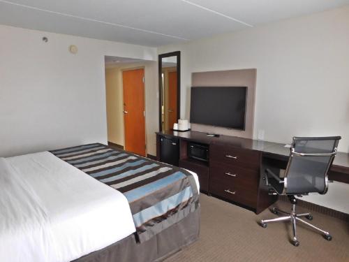 a hotel room with a bed and a desk and a television at Wingate by Wyndham Bowling Green in Bowling Green