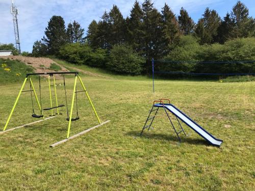 two swings in a field with trees in the background at FAXESTUGORNA in Abbekås