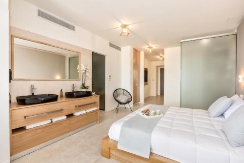 1 dormitorio con 1 cama blanca grande y lavamanos en Lilium Luxury Suites, en Agia Marina de Nea Kydonia