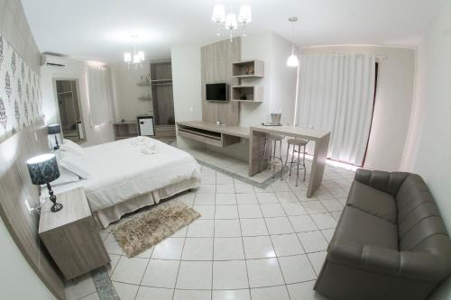 a bedroom with a bed and a desk and a chair at Olinda Hotel e Eventos in Toledo