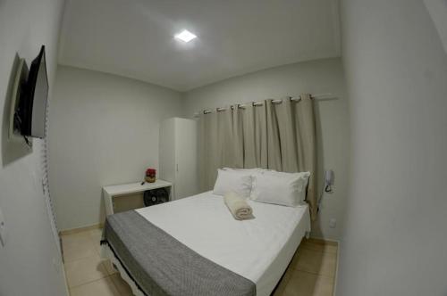 Dormitorio pequeño con cama con sábanas y almohadas blancas en HOTEL CASABLANCA, en Aparecida de Goiania