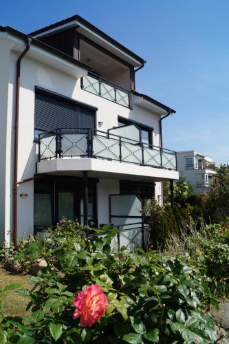 a white building with a balcony and a pink flower at Hotel Villa Undine in Grömitz