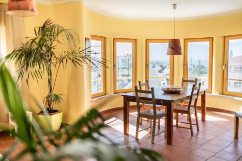 una sala da pranzo con tavolo, sedie e finestre di Peniche Beach House a Peniche