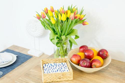 a table with a bowl of apples and a vase of flowers at APARTAMENT 17B BLUE MARINE Poddąbie Basen Odkryty Brodziki Plac Zabaw in Poddąbie