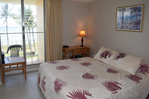 a bedroom with a bed and a table and a window at Hale Kai O'Kihei 305 in Kihei