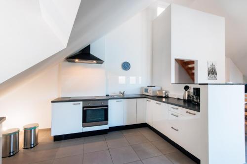 a kitchen with white cabinets and a stove top oven at Les rives de Sax in Dinant