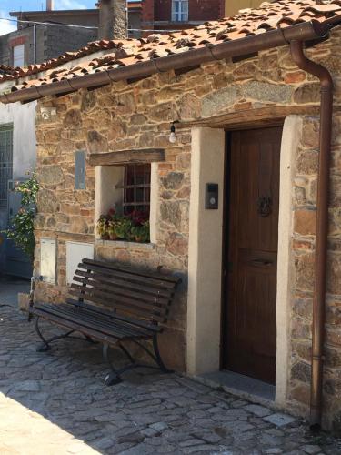a bench in front of a building with a door at Casa Sunalle in Fonni