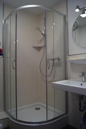 a shower with a glass door next to a sink at Hotel Villa Undine in Grömitz