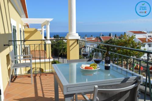 a table with a glass of wine and a bowl of fruit on a balcony at Encantador T1 praia Senhora da Rocha - Algarve in Porches