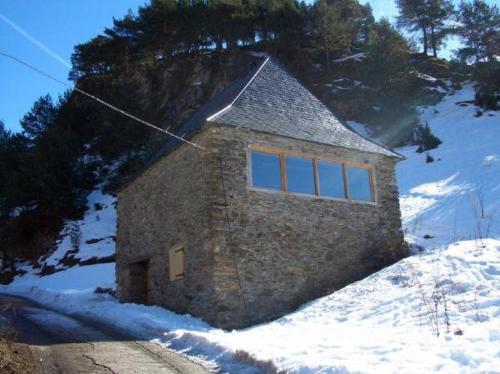 un petit bâtiment en pierre situé au sommet d'une colline enneigée dans l'établissement CABAÑA VENTO NORTE, à Vilamós