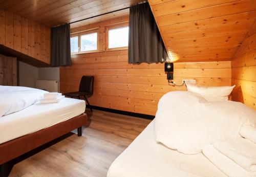 two beds in a room with wooden walls at Haus 4 Montafon by Pferd auf Wolke in Gaschurn