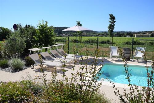 - une piscine avec des chaises et un parasol dans la cour dans l'établissement La maison de Goudargues, à Goudargues