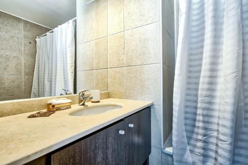 a bathroom with a sink and a shower curtain at Rose Gold - 1BR, Mountain View, Pool, Gym, Mall in Santiago