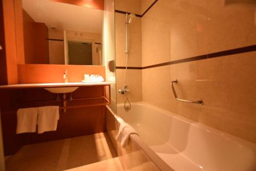 a bathroom with a bath tub and a sink and a bath tub at Hotel Centro Los Braseros in Burgos