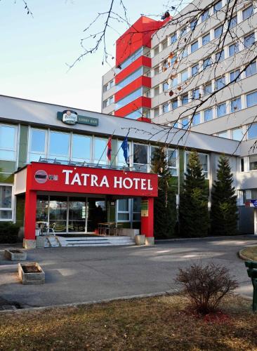 a hotel with a red sign in front of a building at Tatra Hotel in Poprad