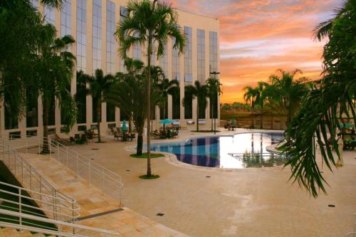 Un edificio con piscina y palmeras en frente. en Barretos Thermas Park - CondoHotel, en Barretos
