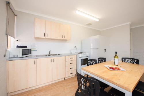 a kitchen with a table and a microwave at Geraldton's Ocean West Holiday Units & Short Stay Accommodation in Geraldton
