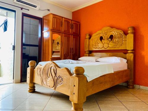 Un dormitorio con una cama de madera con una pared naranja. en Hotel Universitário Goiatuba, en Goiatuba