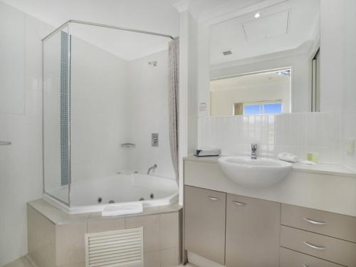 Baño blanco con bañera y lavamanos en Hinterland Luxury - 1 Bedroom Hinterland View Apt, en Ettalong Beach