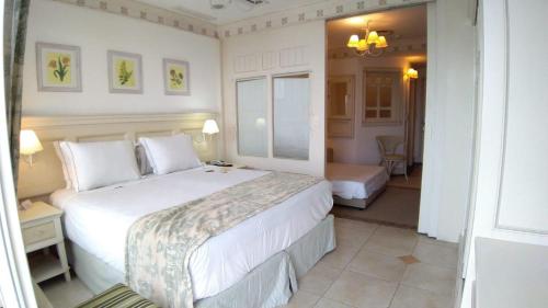 um quarto com uma grande cama branca num quarto em Il Campanario em Florianópolis