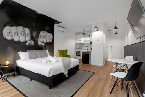 a bedroom with a large bed and a kitchen at SoYa on Davis Apartment Hotel in Melbourne