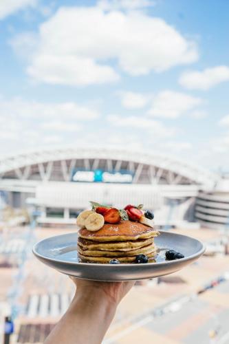 a person holding a plate with pancakes and fruit on it at Novotel Sydney Olympic Park in Sydney