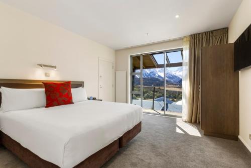 a bedroom with a large bed and a large window at The Hermitage Hotel Mt Cook in Mount Cook Village