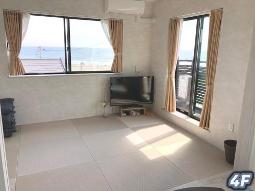 a living room with a flat screen tv and two windows at Purpose Resort Ocean View Kamakura in Kamakura