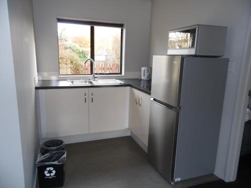 a kitchen with a stainless steel refrigerator and a window at Pinewood Motels in Fairlie