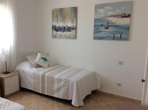 a bedroom with a bed and two pictures on the wall at DUQUESA BY THES SEA - HACIENDA GUADALOUPE in Manilva