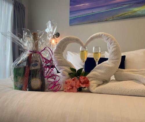 a bed with two towels and two glasses of champagne at Merewether Motel in Newcastle