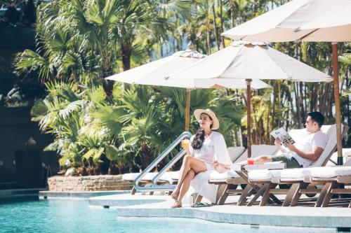 a man and a woman sitting by the pool at a resort at Grand Hyatt Hong Kong in Hong Kong