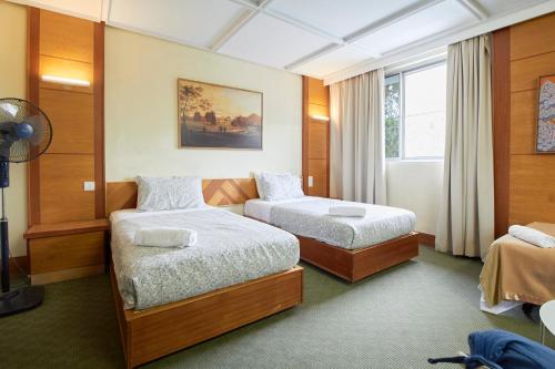 a hotel room with two beds and a window at Bellevue The Penang Hill Hotel, Bukit Bendera in Ayer Itam