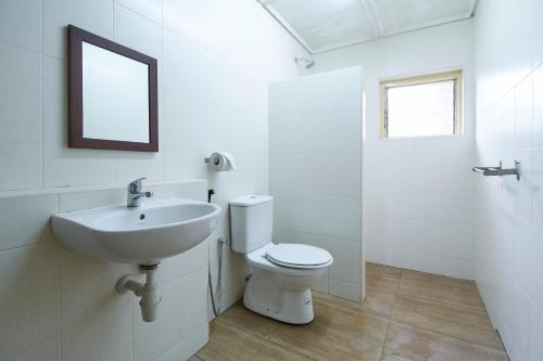 a white bathroom with a toilet and a sink at Bellevue The Penang Hill Hotel in Ayer Itam